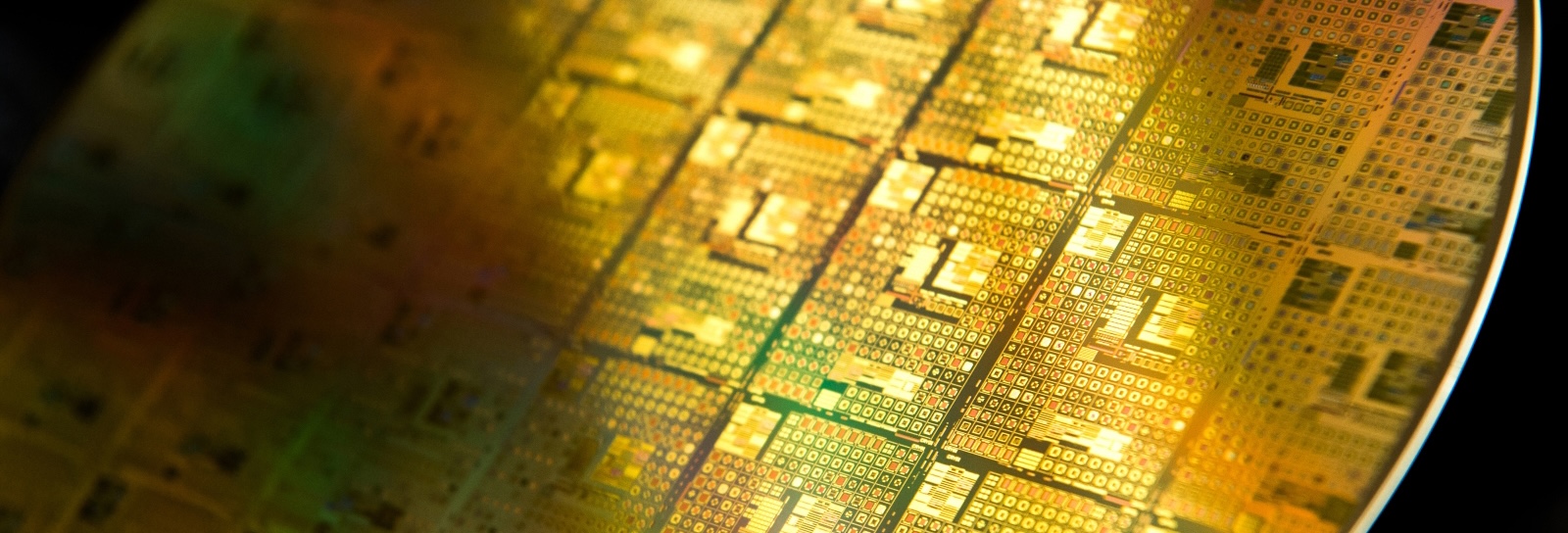 An up-close view of a golden, glimmering semiconductor wafer shows integrated circuits fabricated on the wafer.